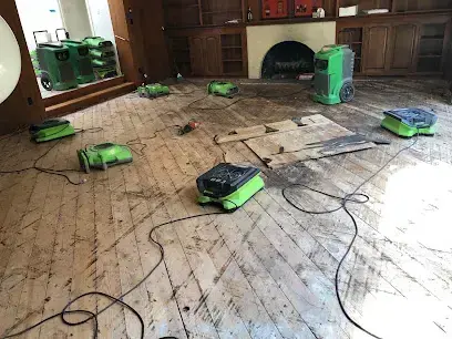 Hardwood floor drying with air movers beside a fireplace in Brentwood, TN